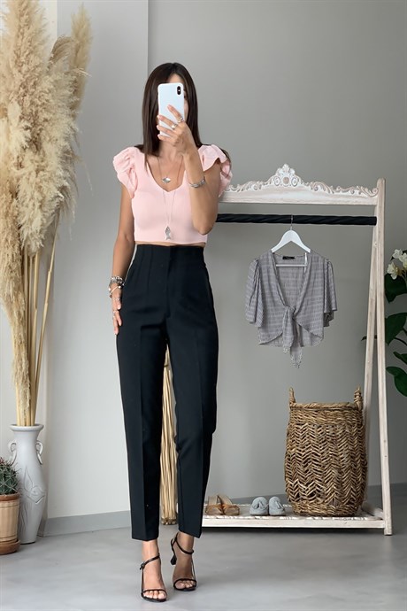siyah pantolon ve krem tişört ile uzun olmaya çalışan kadın